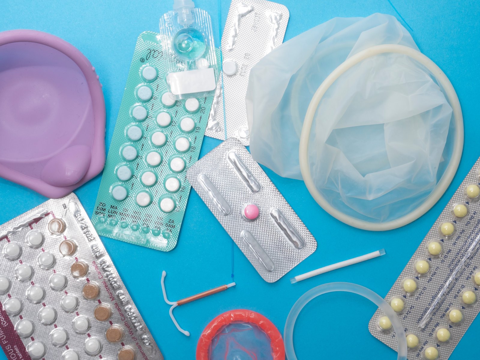 Голубой фон, на котором изображены различные гормональные и безгормональные контрацептивы для женщин